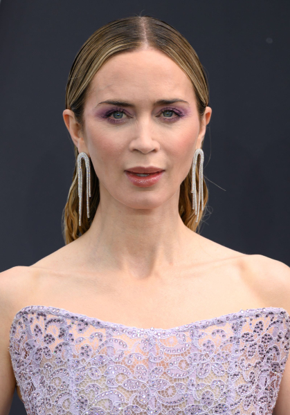 Emily Blunt wears purple eye shadow with a matching dress.